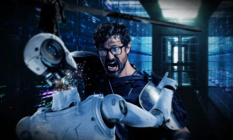 A man in futuristic armor battles a robot in a server room, sparks flying as he destroys its head.