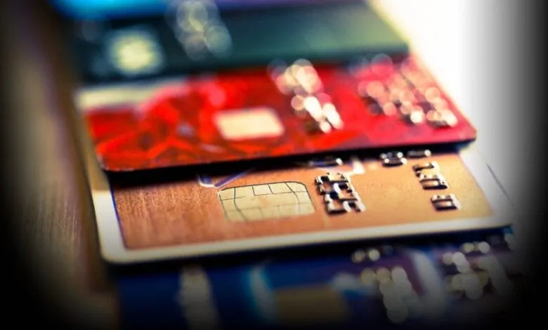 Close-up of several credit cards stacked on a wooden surface, showcasing various colors and designs.