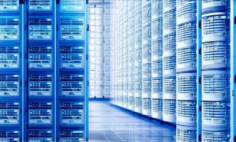 Rows of interconnected server racks in a data center, glowing blue in a dimly lit space.