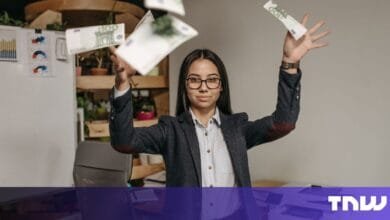 A young businesswoman joyfully throws Euro banknotes into the air, celebrating success in her office.