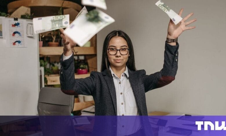 A young businesswoman joyfully throws Euro banknotes into the air, celebrating success in her office.