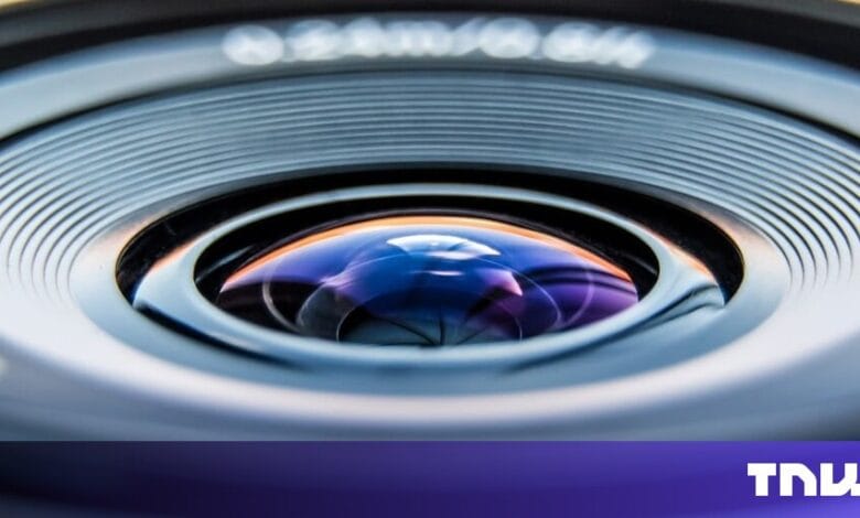 Close-up of a camera lens, showcasing its intricate design and reflective surface with blue and purple hues.