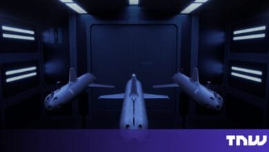 Three futuristic submarines in a dark, metallic hangar, illuminated by bright blue lights.