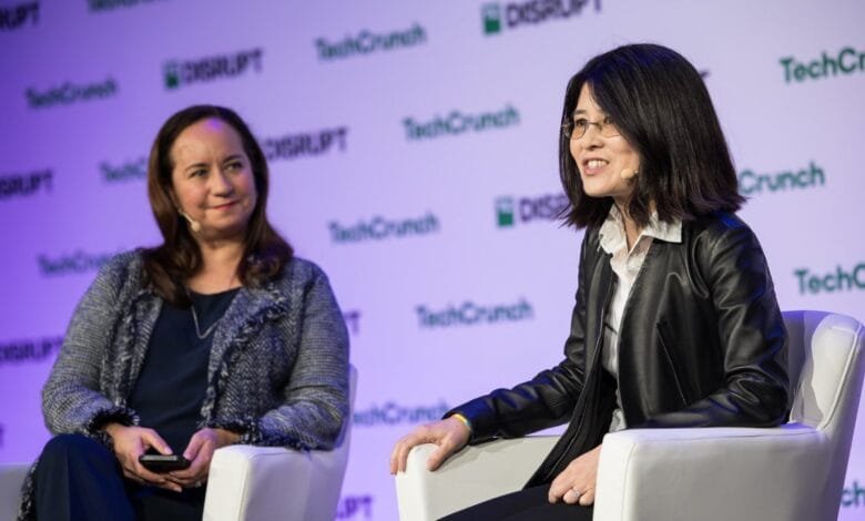 Two women sit on stage at a TechCrunch Disrupt event. One woman wears a black leather jacket, the other a tweed jacket.