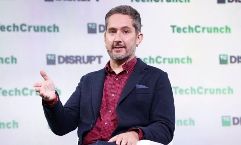 Kevin Systrom, Instagram co-founder, speaks at TechCrunch Disrupt, gesturing while on stage. Green and white branding is visible.
