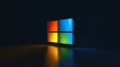 Glowing Windows logo in orange, blue, yellow, and green on a dark reflective surface.