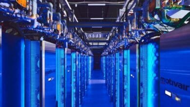 Rows of blue-lit server racks in a data center extend into the distance, showcasing advanced technology and infrastructure.