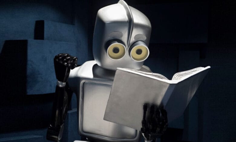 A silver robot with large, expressive eyes sits in a dark room, engrossed in reading a book.