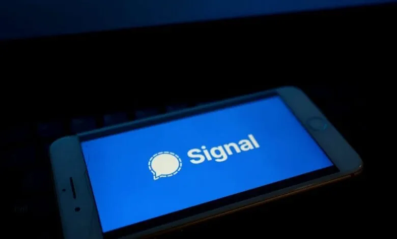Smartphone displaying Signal app's bright blue screen with its white logo: a speech bubble with a dashed outline.