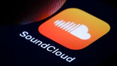 Close-up of a finger about to tap the SoundCloud app icon on a smartphone. The icon is orange and white.