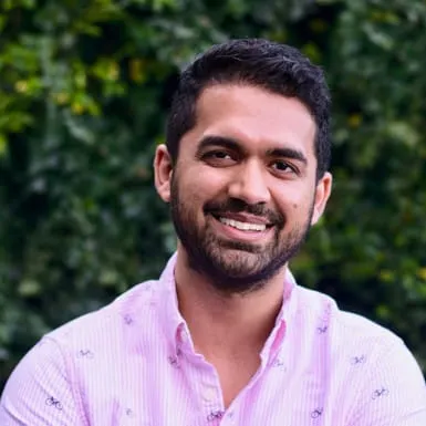 Smiling man, Sankaet Pathak, with dark hair and beard wearing a light pink shirt with a subtle pattern.