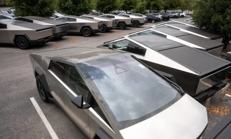 A fleet of silver Tesla Cybertrucks parked in a lot, showcasing their unique angular design.