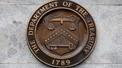 Close-up of the bronze seal of the US Department of the Treasury, featuring scales, a key, and the year 1789.