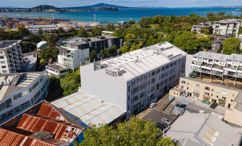 Aerial view of Future Houses building in Auckland, New Zealand, with harbor and city in background.