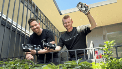 Two men stand on a balcony, holding several high-end graphics cards. One shirt says 'LLMs will never be the same'.
