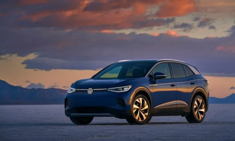 Sleek, dark-blue Volkswagen ID.4 electric SUV parked on a salt flat at sunset.