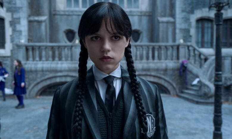 Wednesday Addams, from the Netflix series, stares intensely at the camera, wearing her signature Nevermore Academy uniform.