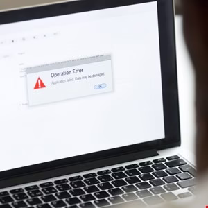Laptop screen displays an 'Operation Error' message, indicating application failure and potential data damage.
