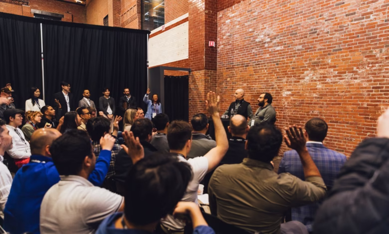 Audience participates in a Q&A session with panelists at a conference in a brick-walled room.