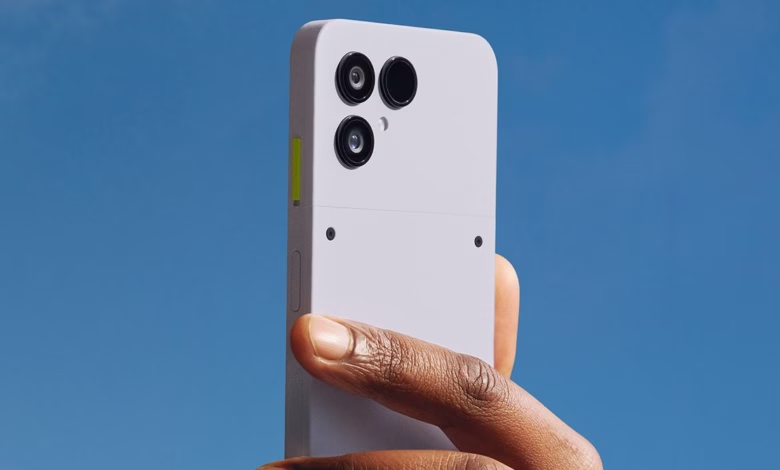 A hand holds up a light purple Fairphone, showcasing its triple-lens camera against a clear blue sky.