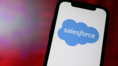 Close-up of a smartphone displaying the Salesforce logo, a blue cloud with the word 'salesforce' inside.