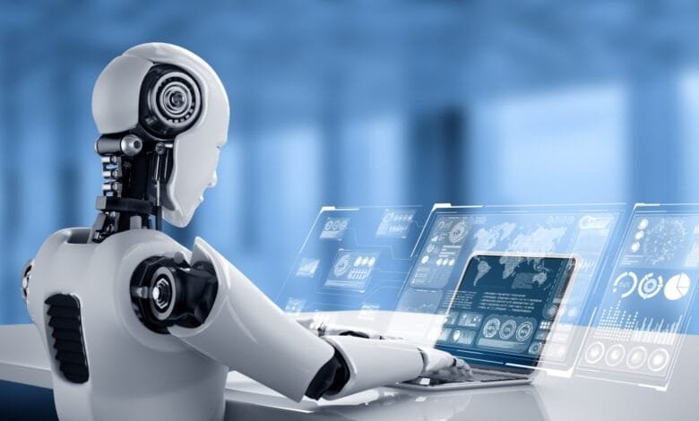 A white robot sits at a desk using a laptop with holographic displays showing data charts and graphs.