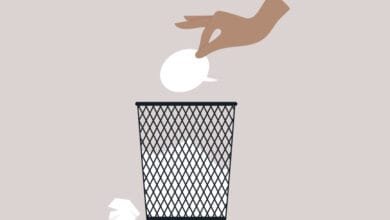 Hand throws speech bubble into trash can; visual metaphor for censorship or silencing of voices.