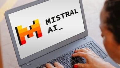Laptop displaying the Mistral AI logo and text. A person's hands are typing on the keyboard.