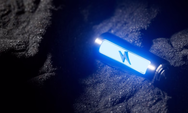 Futuristic solid-state battery rests on dark surface, glowing blue with a stylized lightning bolt logo.