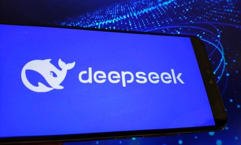 Close-up of a smartphone displaying the DeepSeek logo on a bright blue background. A blurry blue data visualization is in the background.