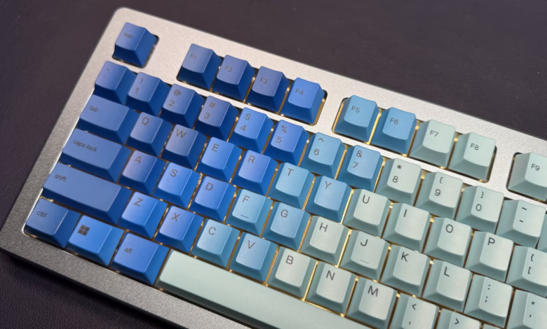 Close-up of a custom mechanical keyboard with a blue and teal gradient keycap set and a silver aluminum frame.