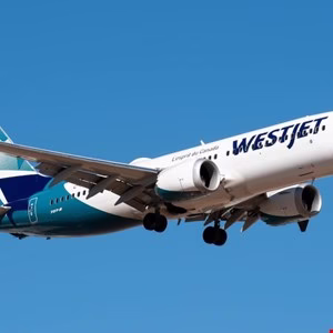 WestJet Boeing 737 airplane in flight against a clear blue sky.