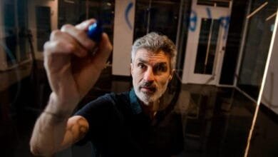 Yoshua Bengio, a renowned computer scientist, writes on a glass wall with a blue marker.