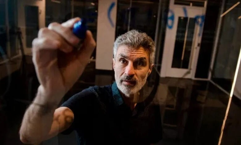 Yoshua Bengio, a renowned computer scientist, writes on a glass wall with a blue marker.