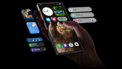 Hand holding smartphone displaying cat photo, weather, step count, and music player widgets. Notifications and other app icons are visible.