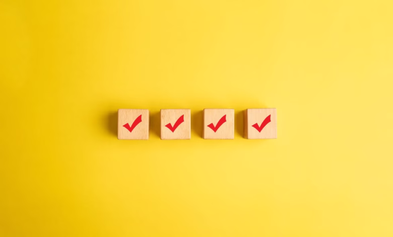 Four wooden blocks with red checkmarks arranged in a row on a yellow background.