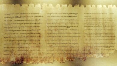 Close-up of an ancient, fragmented parchment scroll displaying faded text in an unknown script.