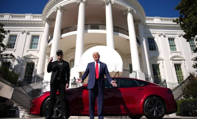 Donald Trump and Elon Musk stand before the White House with a red Tesla.