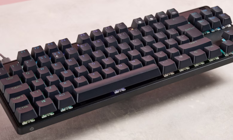 A black SteelSeries Apex Pro TKL wireless keyboard floats slightly above a light gray surface.