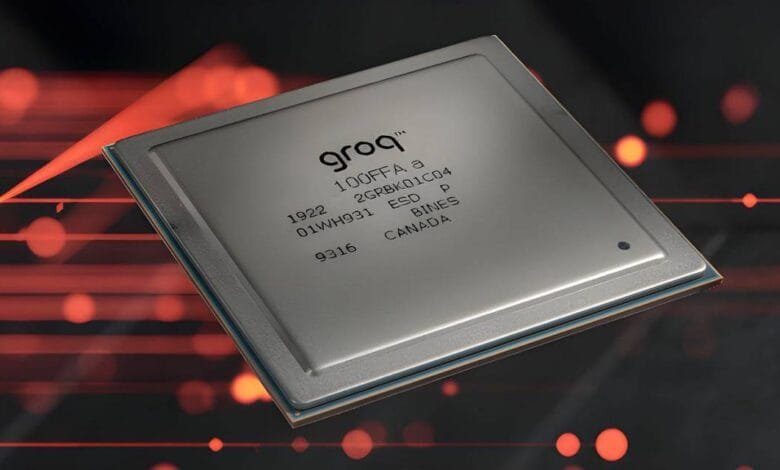 Close-up of a Groq processor chip, silver with black text, against a blurred red and black background.