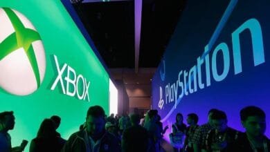 Large Xbox and PlayStation displays at a gaming convention, with attendees walking between them.