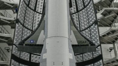 Close-up view of a spacecraft's heat shield, showing numerous small, circular vents and the USAF insignia.