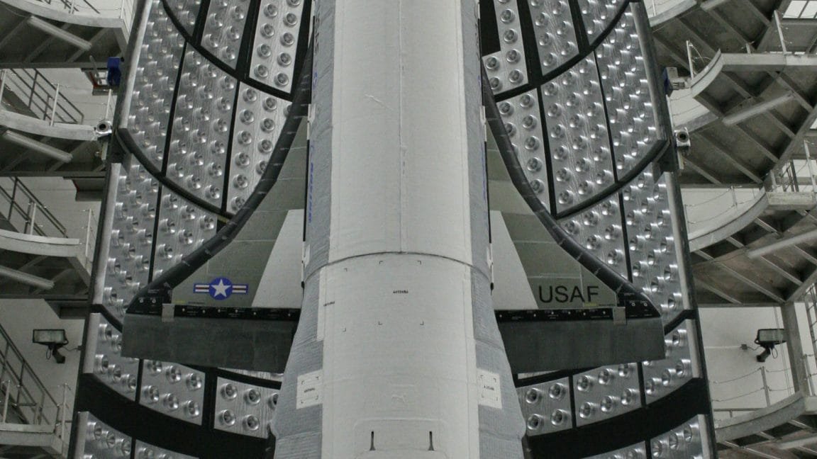 Close-up view of a spacecraft's heat shield, showing numerous small, circular vents and the USAF insignia.