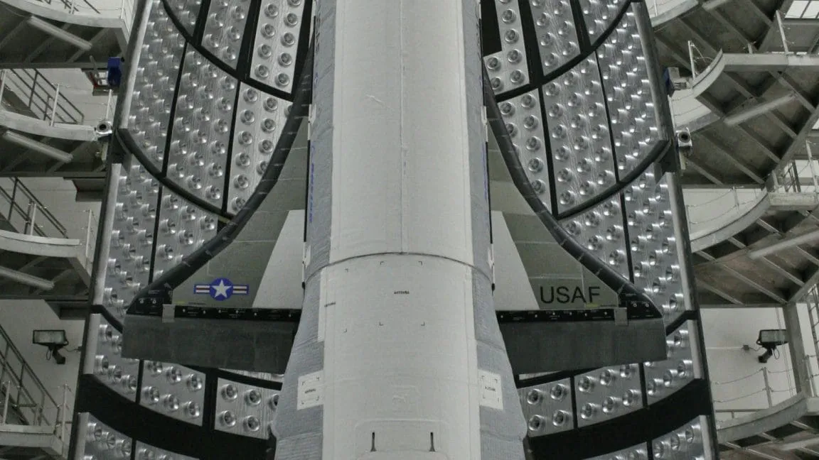 Close-up view of a spacecraft's heat shield, showing numerous small, circular vents and the USAF insignia.