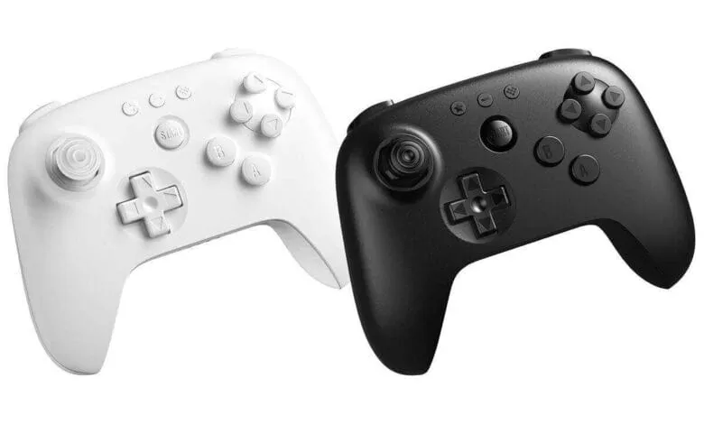 Pair of wireless game controllers, one white and one black, shown from an angled view.