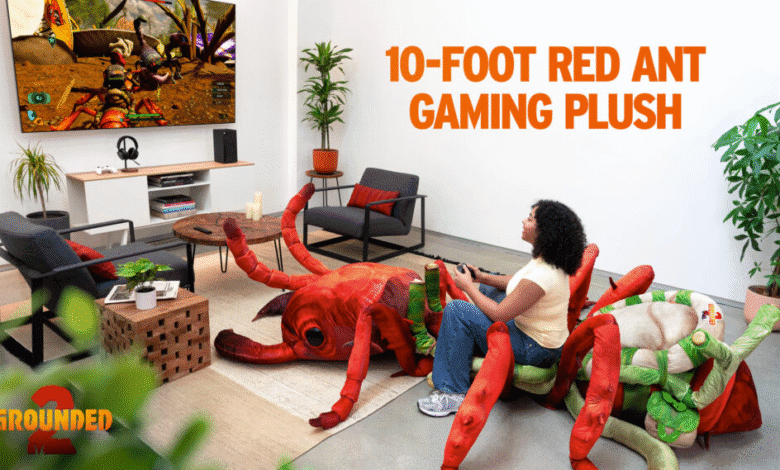 Person plays video game while sitting on a giant red ant plush toy. The game on screen shows insect-like creatures.