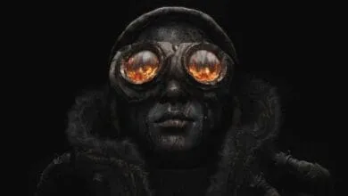 Close-up of a person wearing dark, worn clothing and goggles with fiery reflections in the lenses, set against a black background.