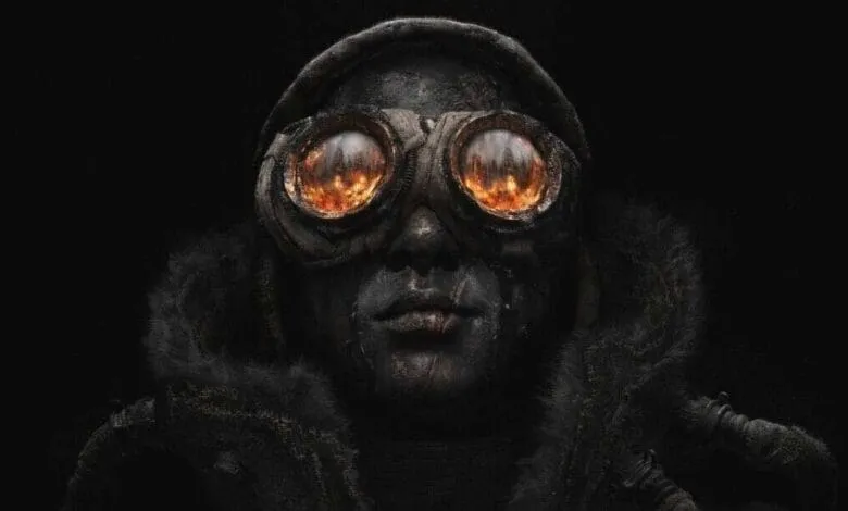 Close-up of a person wearing dark, worn clothing and goggles with fiery reflections in the lenses, set against a black background.