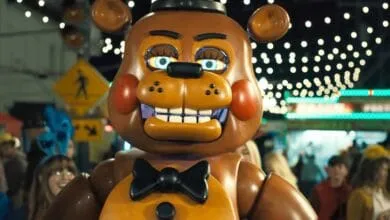 A large animatronic Freddy Fazbear from Five Nights at Freddy's walks through a nighttime festival.