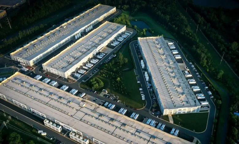 Aerial view of a large data center campus with multiple white buildings and surrounding greenery.